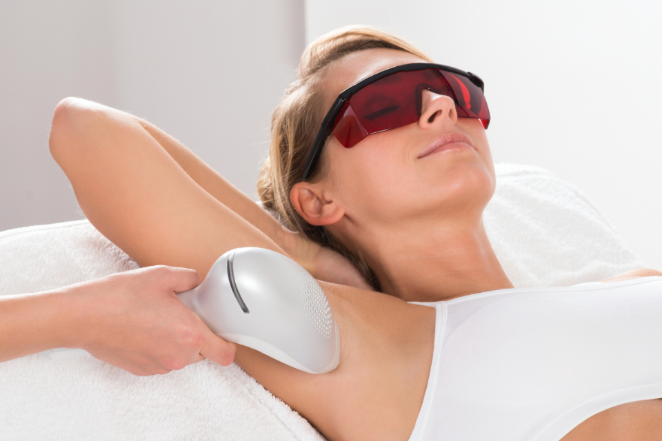 Young woman having underarm laser hair removal treatment in a beauty spa.
